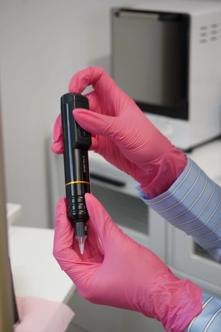 Permanent makeup machine held in gloved hands